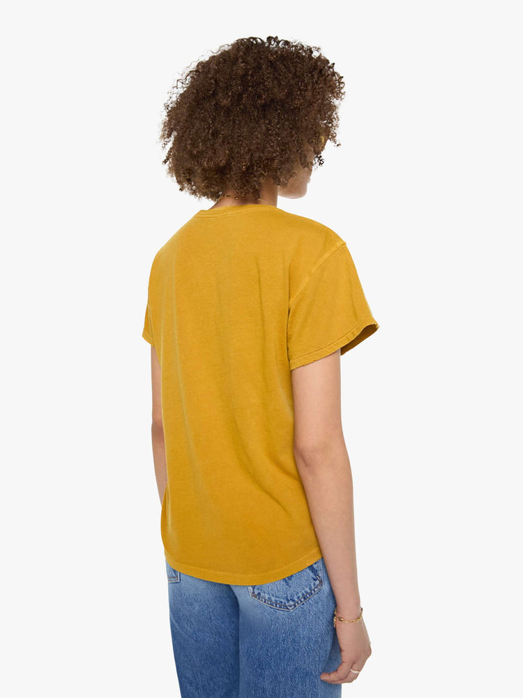 Back view of a woman in a mustard yellow tee that pays homage to Fleetwood Mac with a colorful penguin portrait and text on the front.