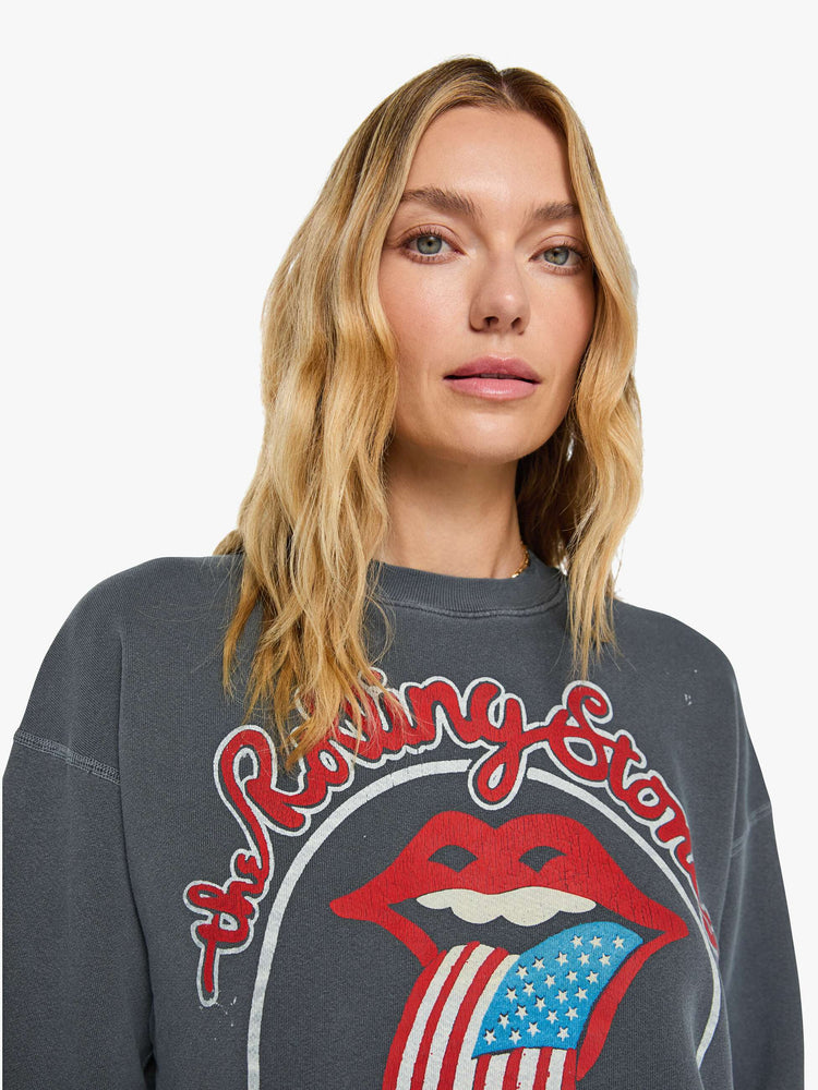 Close up view of a woman in dark grey sweatshirt pays homage to The Rolling Stones with the band's iconic tongue graphic on the front.