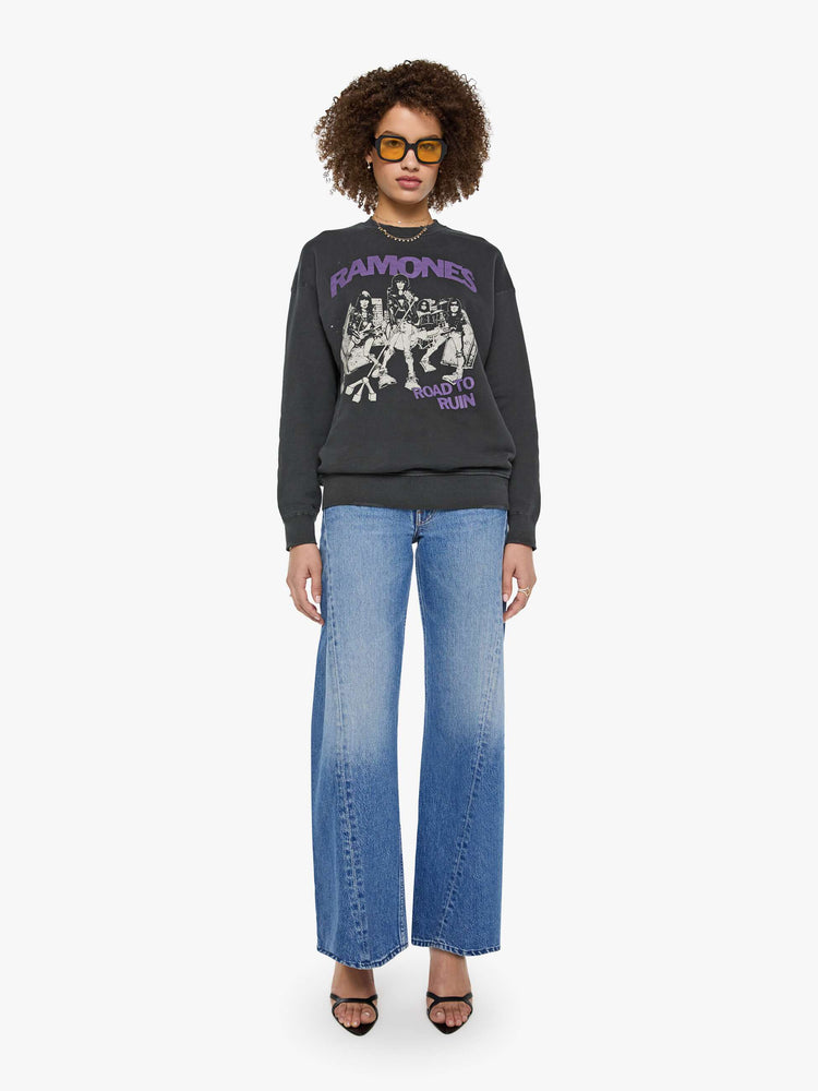 Full body view of a woman in a faded black sweatshirt pays homage to The Ramones' eleventh studio album with a cream graphic and the band's name in purple on the front.