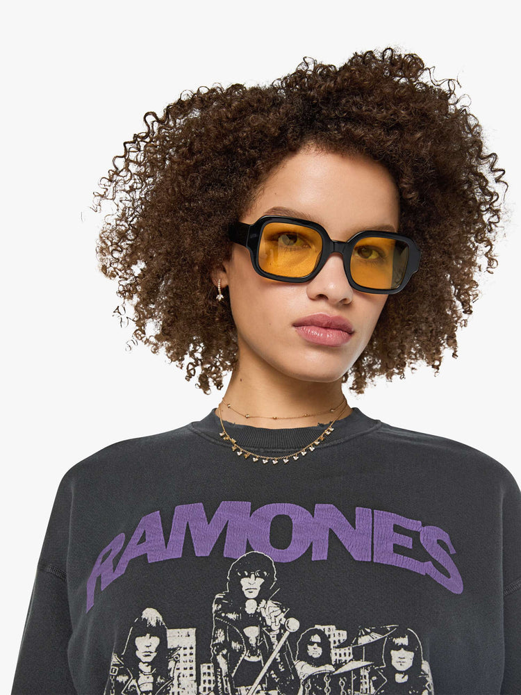 Close up view of a woman in a faded black sweatshirt pays homage to The Ramones' eleventh studio album with a cream graphic and the band's name in purple on the front.
