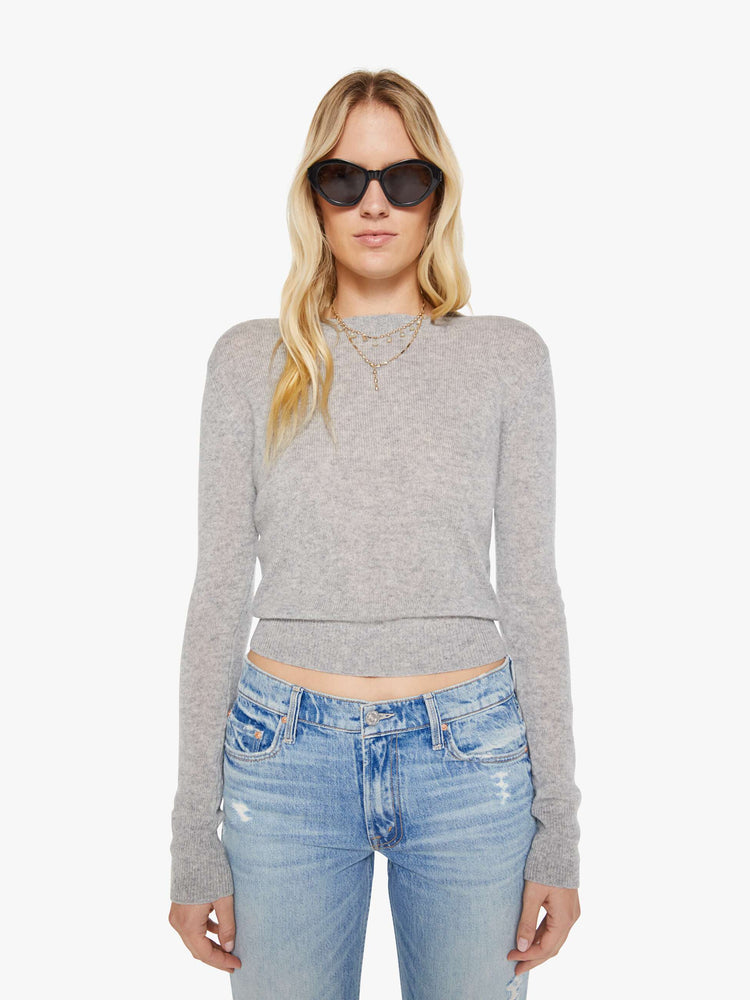 Front view of a woman in a grey sweater is designed with ribbed hems and a cropped fit.