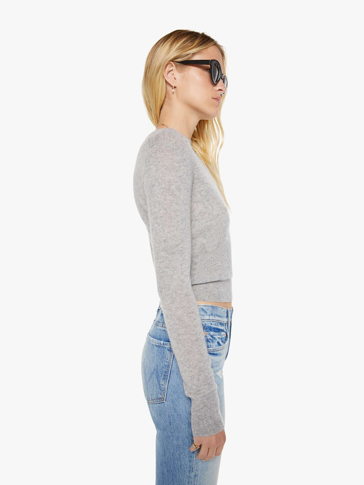 Side view of a woman in a grey sweater is designed with ribbed hems and a cropped fit.