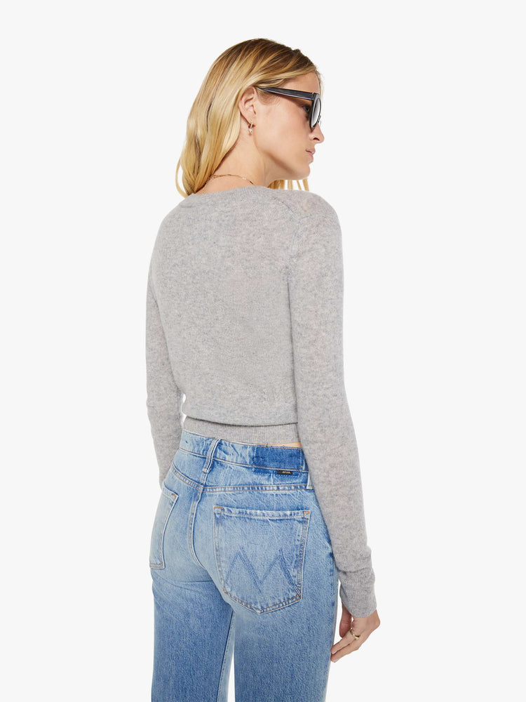 Back view of a woman in a grey sweater is designed with ribbed hems and a cropped fit.