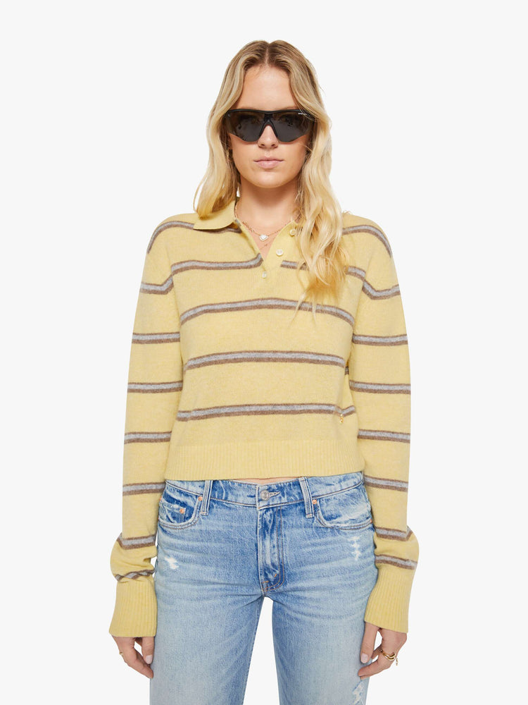 Front view of a woman in a butter yellow sweater with horizontal blue stripes, the sweater is designed with a buttoned neck, long sleeves, ribbed hems and a cropped fit. 