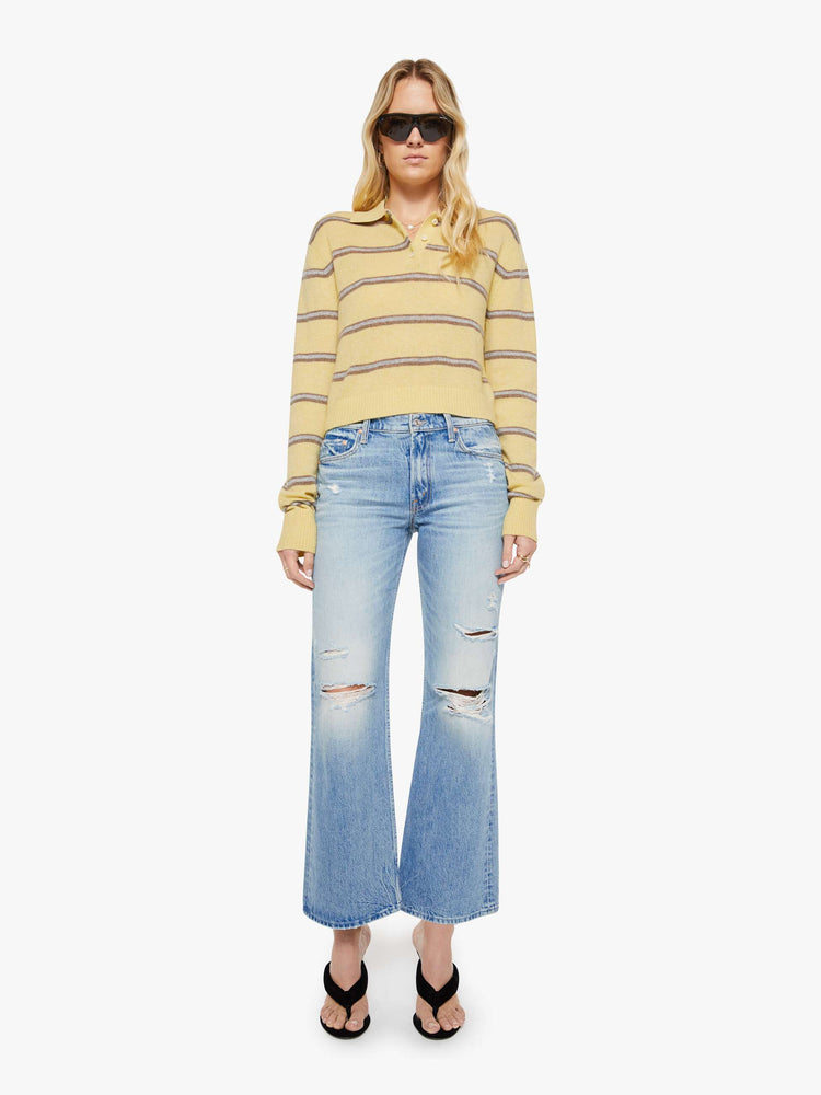 Full body view of a woman in a butter yellow sweater with horizontal blue stripes, the sweater is designed with a buttoned neck, long sleeves, ribbed hems and a cropped fit. 