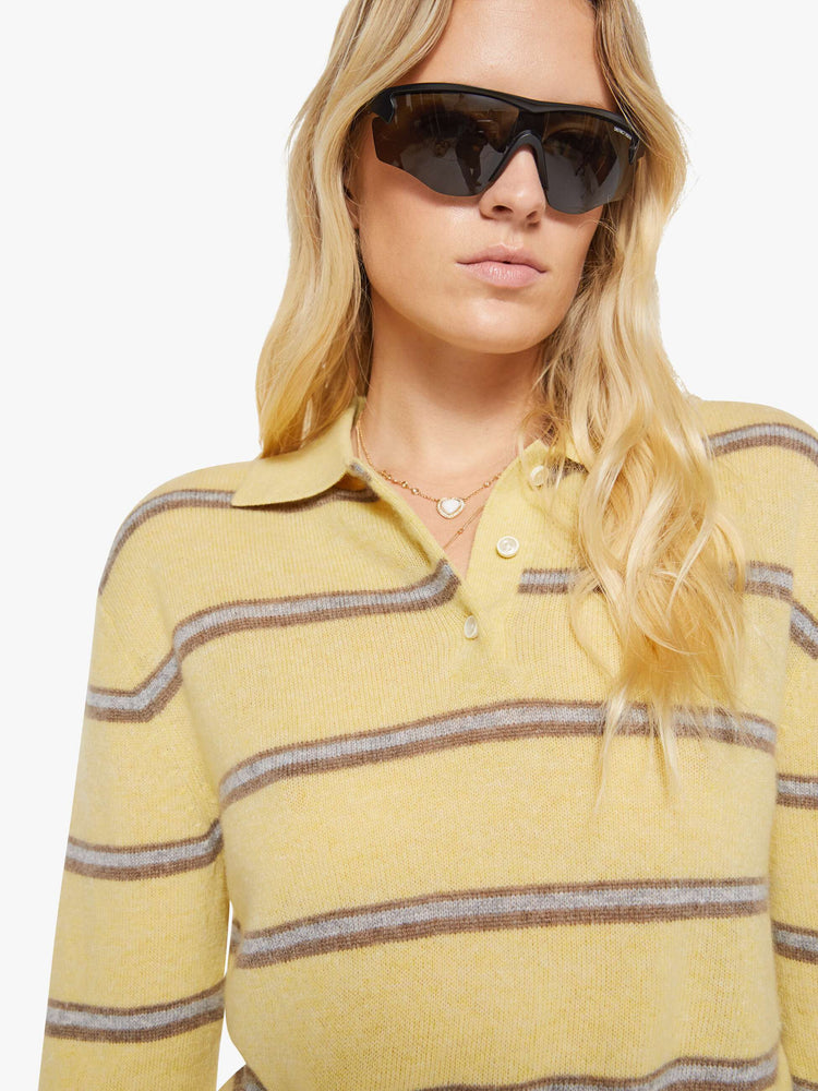 Close up view of a woman in a butter yellow sweater with horizontal blue stripes, the sweater is designed with a buttoned neck, long sleeves, ribbed hems and a cropped fit. 