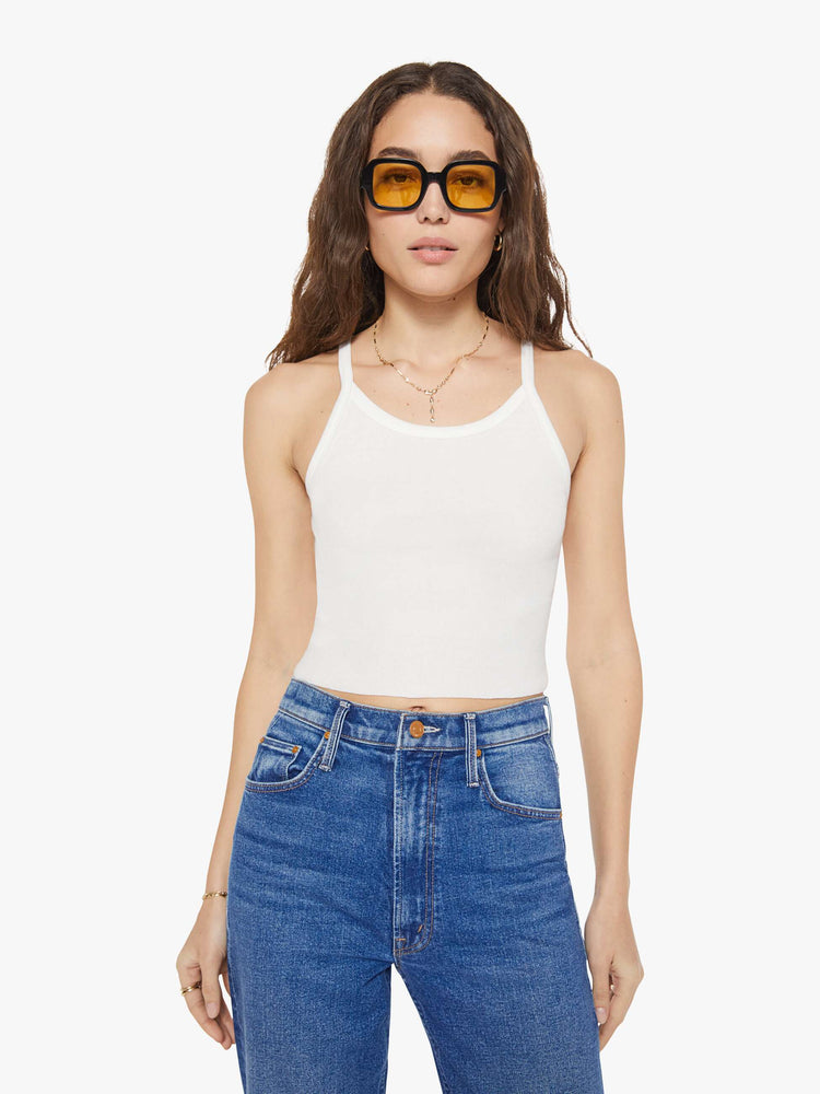 Front view of a woman in a white tank designed with thin spaghetti straps, a scoop neck and cropped fit.