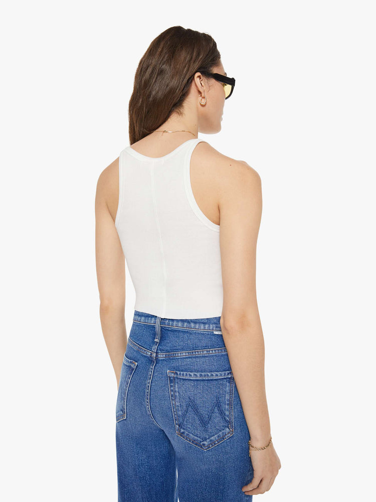 Back view of a woman in a white tank designed with thin spaghetti straps, a scoop neck and cropped fit.