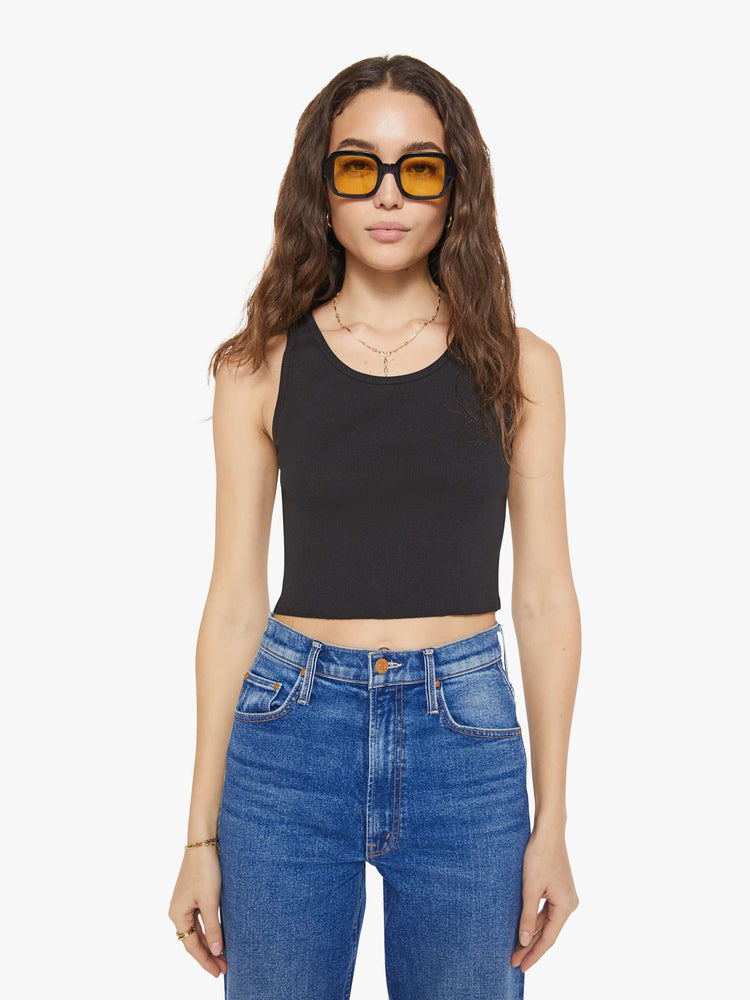 Front view of a woman in a black scoop neck tank is designed with a cropped fit.