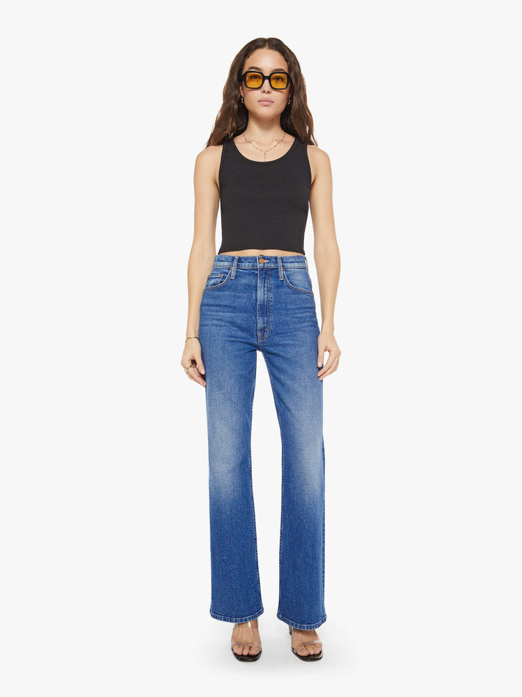 Full body view of a woman in a black scoop neck tank is designed with a cropped fit.
