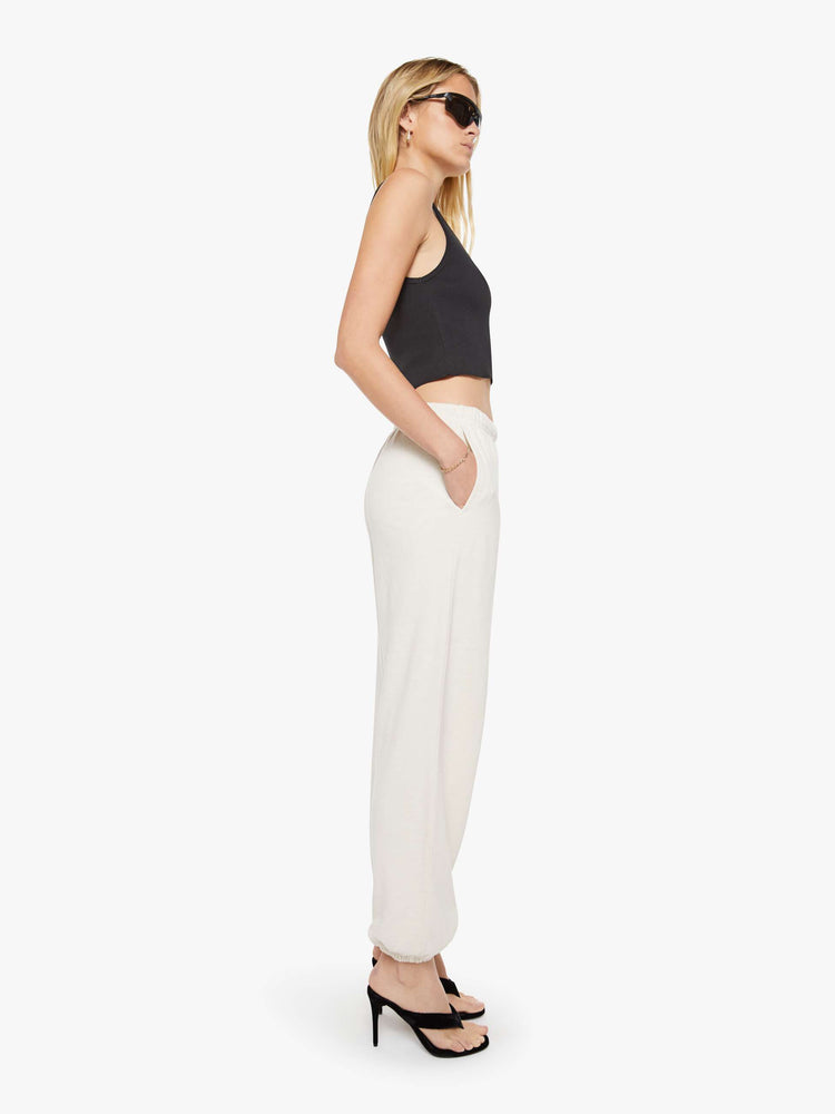 Side view of a woman in a white Boyfriend Pocket Sweatpant with an elastic waistband and hems, a wide leg, slit pockets and a loose, cozy fit.