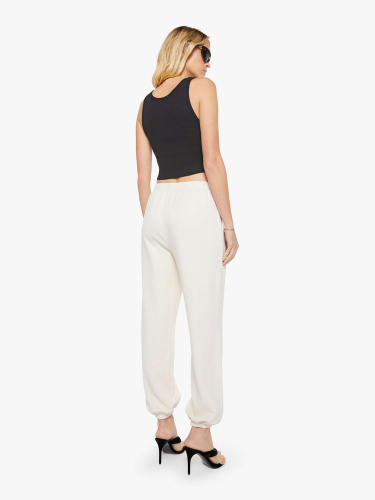 Back view of a woman in a white Boyfriend Pocket Sweatpant with an elastic waistband and hems, a wide leg, slit pockets and a loose, cozy fit.