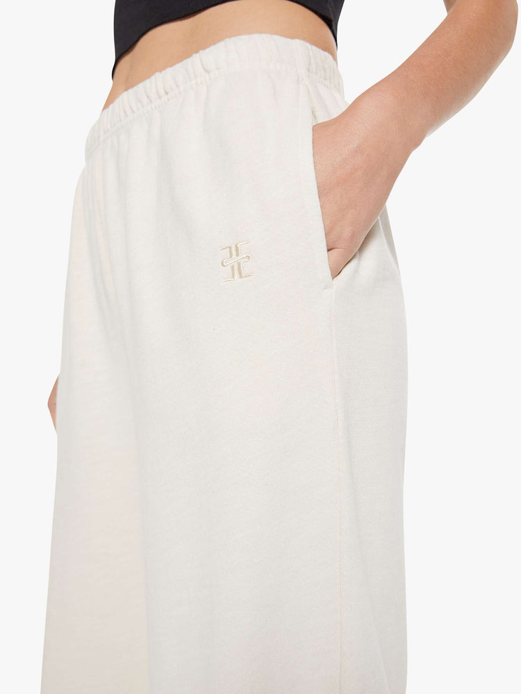 Close up view of a woman in a white Boyfriend Pocket Sweatpant with an elastic waistband and hems, a wide leg, slit pockets and a loose, cozy fit.