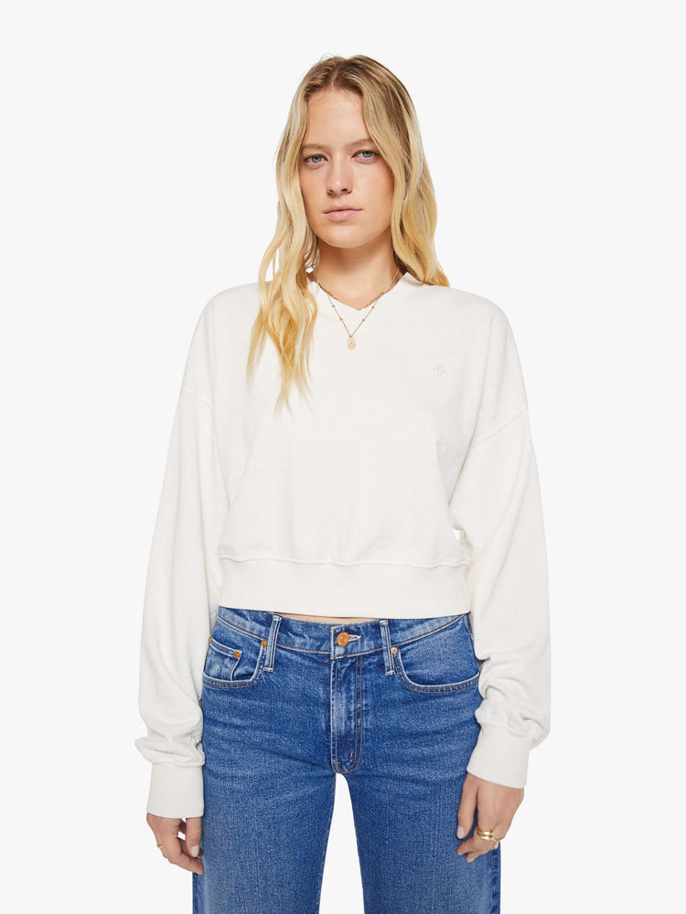 Front view of a woman in a white sweatshirt with a short V-neck, drop shoulders, ribbed hems and a cropped, cozy fit.