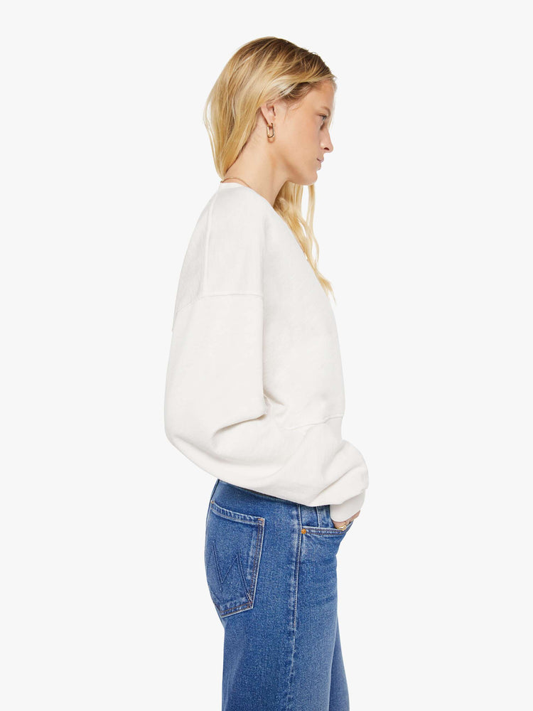 Side view of a woman in a white sweatshirt with a short V-neck, drop shoulders, ribbed hems and a cropped, cozy fit.