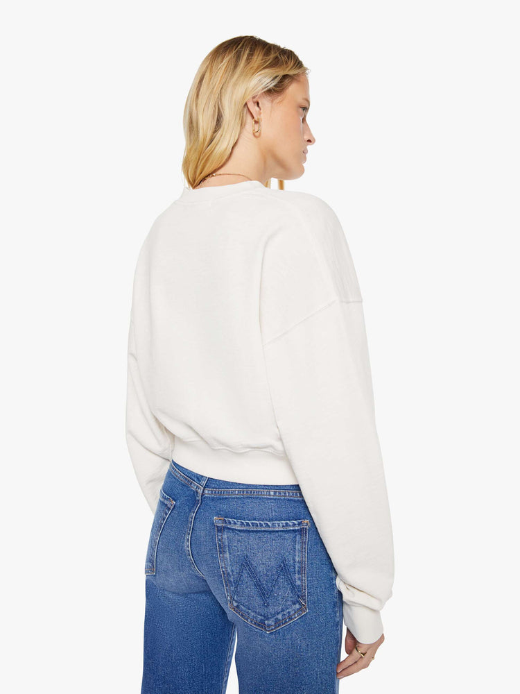 Back view of a woman in a white sweatshirt with a short V-neck, drop shoulders, ribbed hems and a cropped, cozy fit.