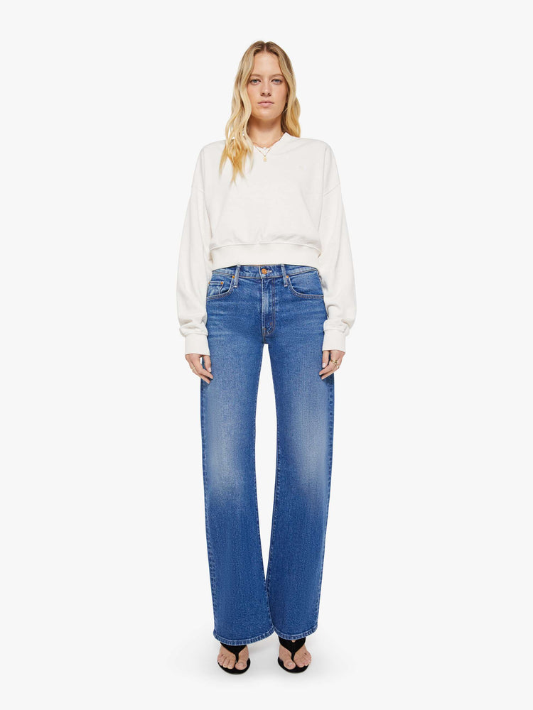 Full body view of a woman in a white sweatshirt with a short V-neck, drop shoulders, ribbed hems and a cropped, cozy fit.