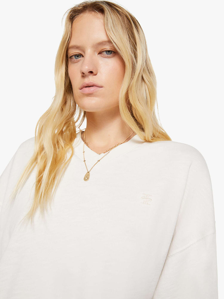 Close up view of a woman in a white sweatshirt with a short V-neck, drop shoulders, ribbed hems and a cropped, cozy fit.
