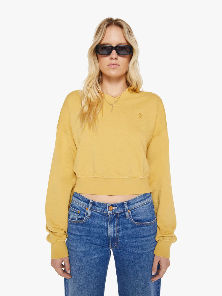 Front view of a woman in a yellow  sweatshirt with a short V-neck, drop shoulders, ribbed hems and a cropped, cozy fit. 