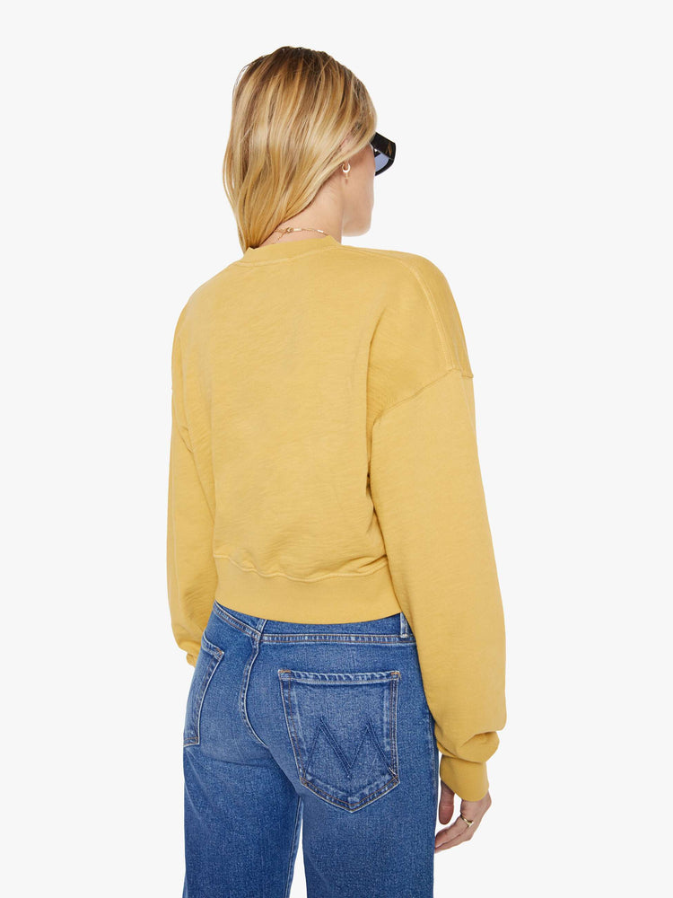 Back view of a woman in a yellow  sweatshirt with a short V-neck, drop shoulders, ribbed hems and a cropped, cozy fit. 