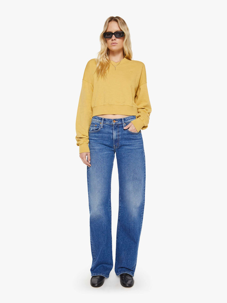 Full body view of a woman in a yellow  sweatshirt with a short V-neck, drop shoulders, ribbed hems and a cropped, cozy fit. 