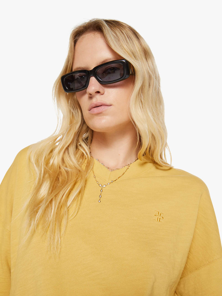 Close up view of a woman in a yellow  sweatshirt with a short V-neck, drop shoulders, ribbed hems and a cropped, cozy fit. 
