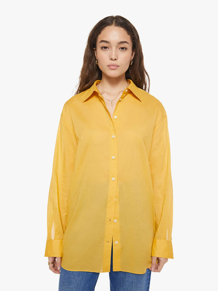 Front view of a woman in a golden yellow oversized button-up shirt.