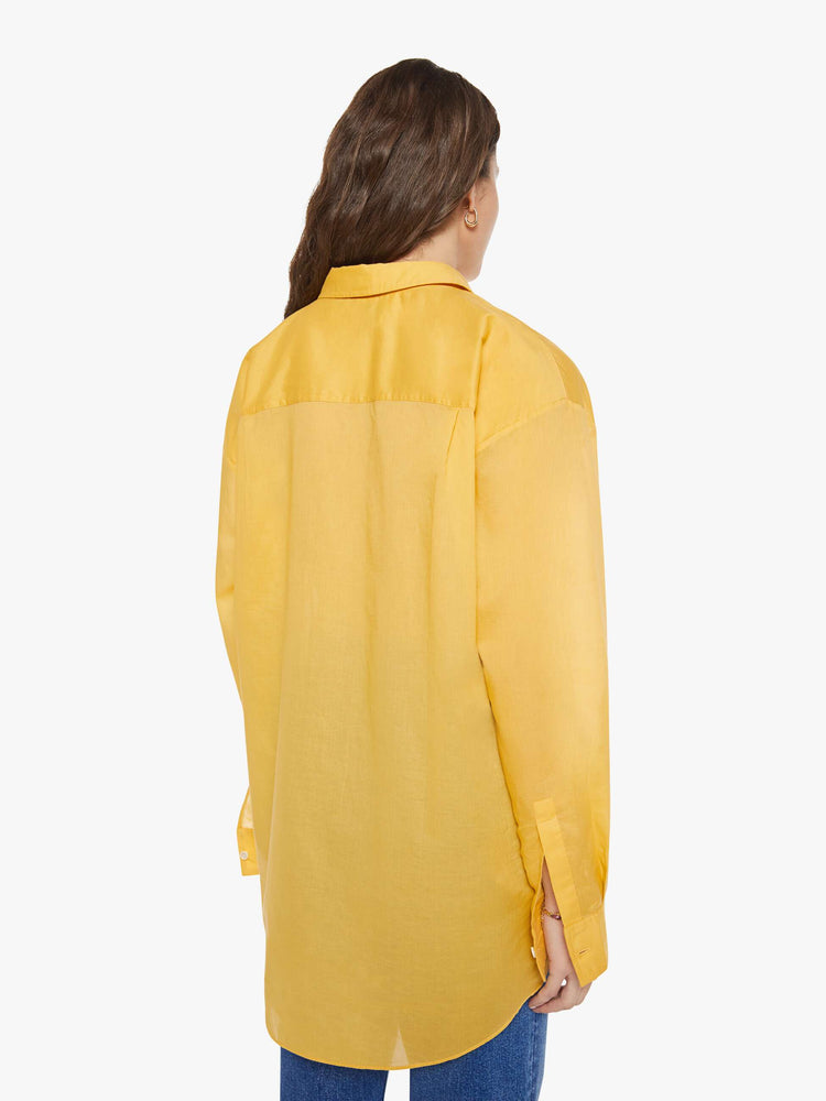 Back view of a woman in a golden yellow oversized button-up shirt.