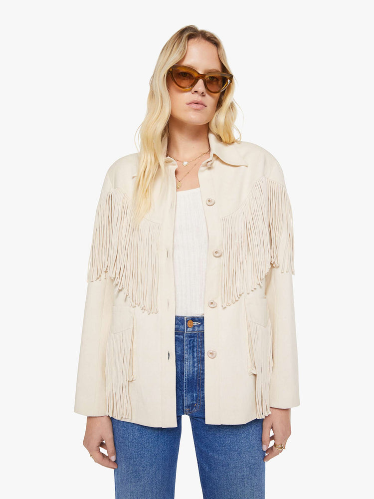 Front view of a woman in a cream with fringe details jacket it has slightly dropped shoulders, front patch pockets, buttons down the front and a boxy fit.