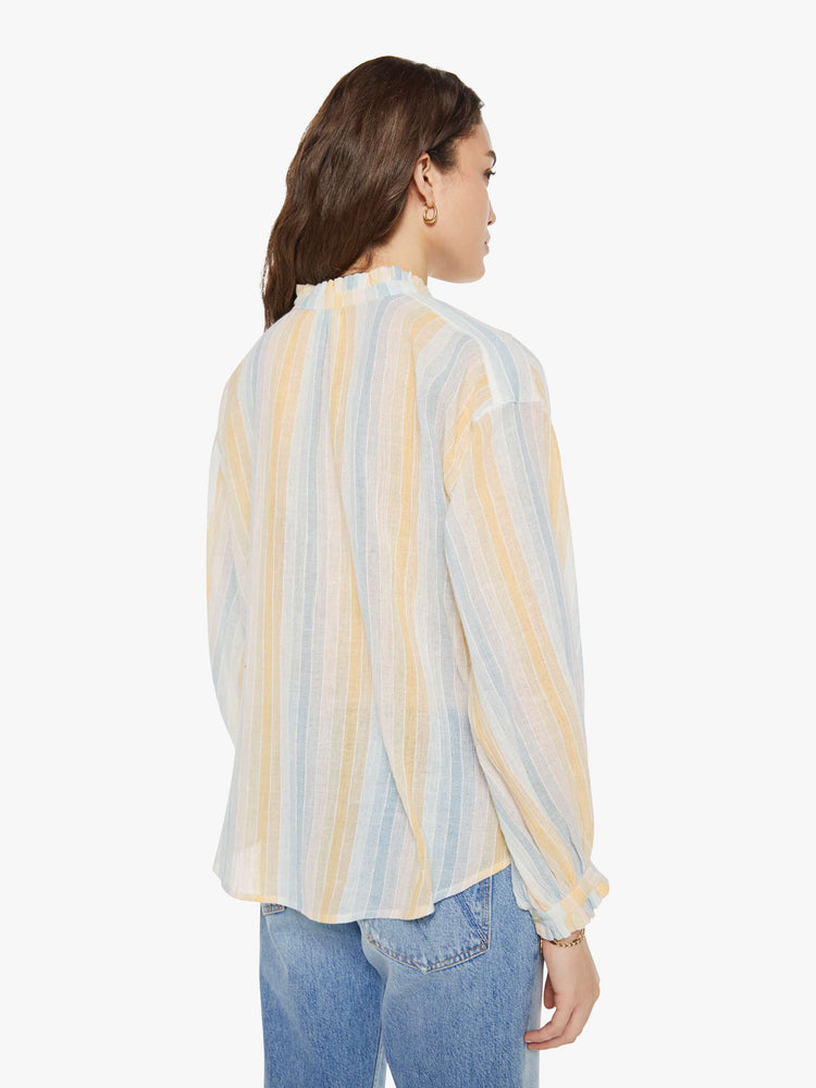 Back view of a woman in a vertical yellow, white and light blue stripes, and features a stacked collar shirt, drop shoulders, long balloon sleeves and a curved hem.