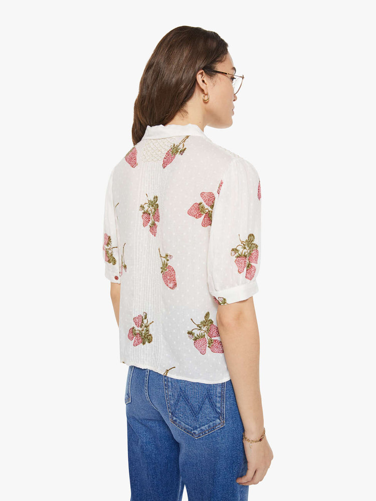 Back view of a woman in an off-white shirt with a faded strawberry print, and is designed with a collared neck, short sleeves and buttons down the front.