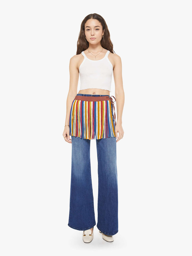 Front view of a woman in fringe mini skirt is made from 100% silk in colorful vertical stripes and features a side tie closure and thigh-length hem. Wear it over your favorite MOTHER jeans.