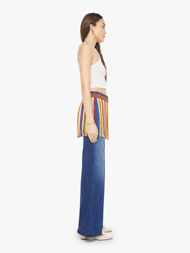 Side view of a woman in fringe mini skirt is made from 100% silk in colorful vertical stripes and features a side tie closure and thigh-length hem. Wear it over your favorite MOTHER jeans.