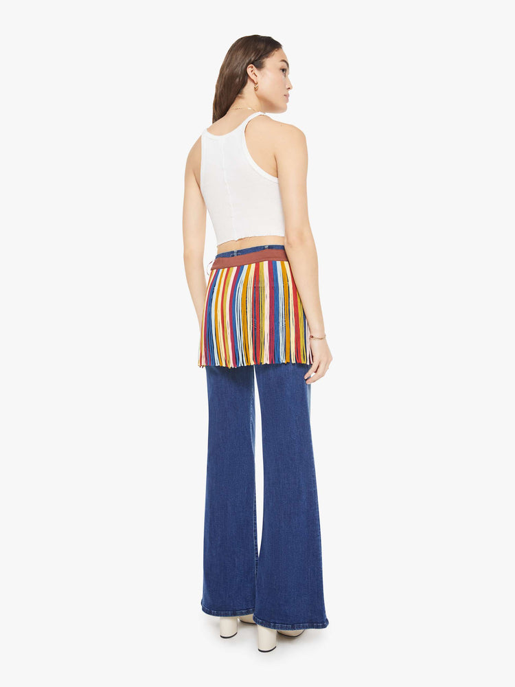 Back view of a woman in fringe mini skirt is made from 100% silk in colorful vertical stripes and features a side tie closure and thigh-length hem. Wear it over your favorite MOTHER jeans.