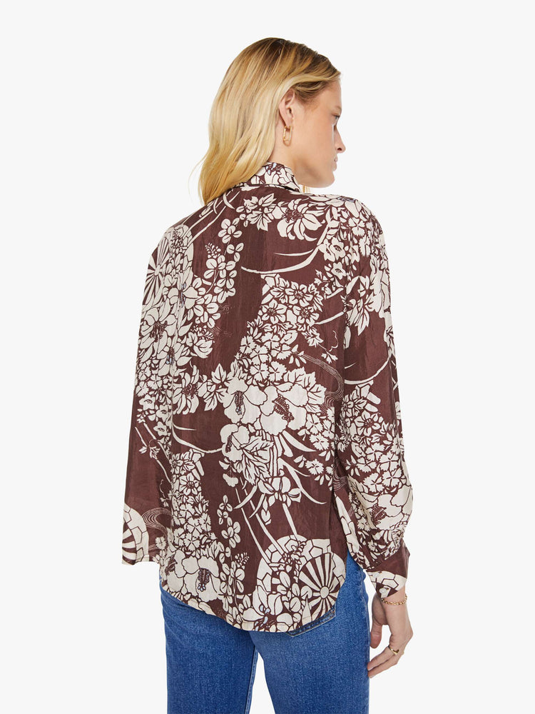 Back view of a woman in a brown with a white vintage-inspired print shirt that features drop shoulders, long sleeves, curved hems and buttons down the front.