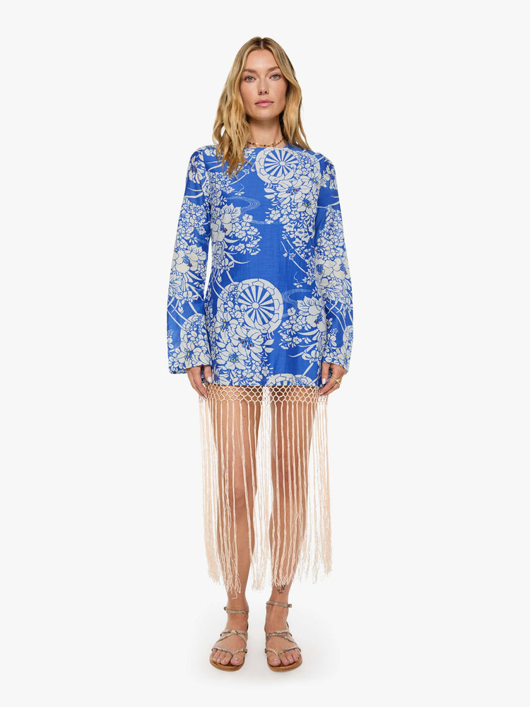 Front view of a woman in a blue with a white vintage-inspired print dress and features a crewneck, long sleeves and fringe that hits at the ankle.