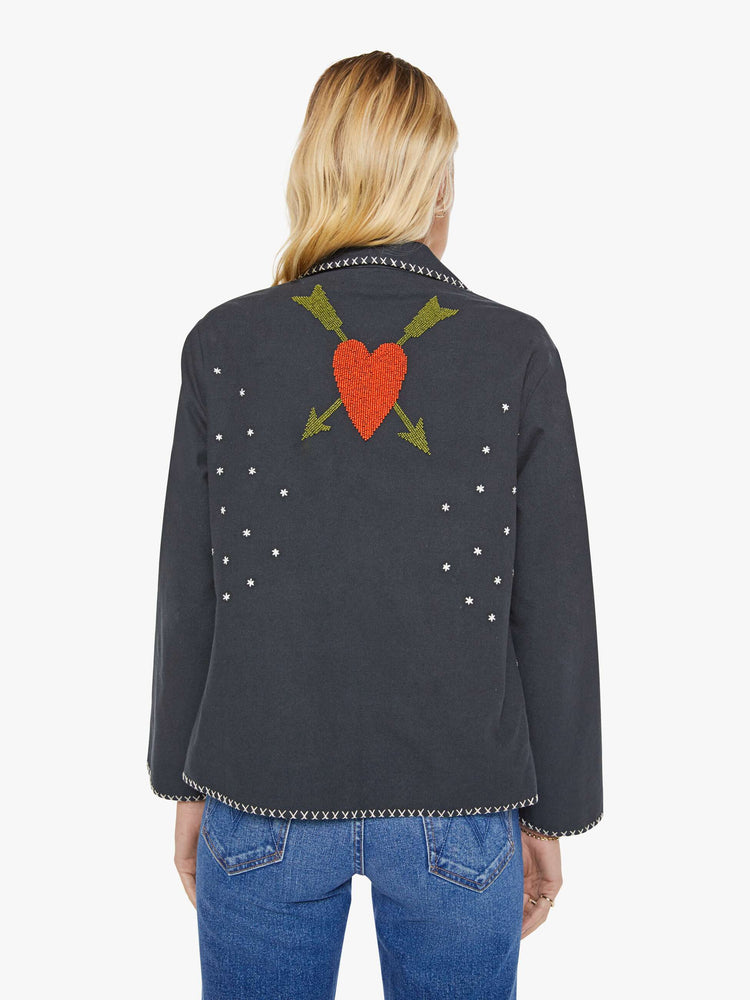 Back view of a woman in a  faded grey jacket features horse motifs throughout. It has slightly dropped shoulders, front patch pockets and a tailored fit that hugs the body like a blazer. 