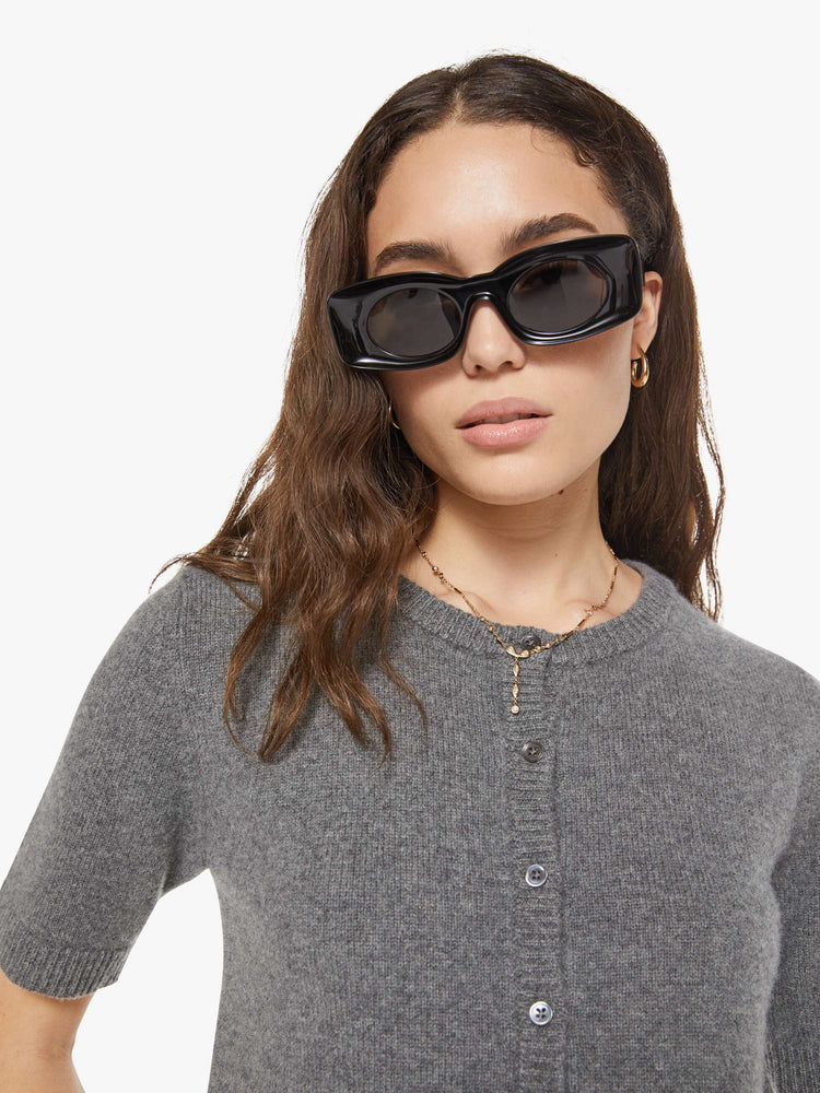 Close up view of a woman in short-sleeve cardigan from the Los Angeles brand SPRWMN (pronounced "superwoman") Made from 100% cashmere in grey, the sweater has a crewneck and a slightly cropped fit.