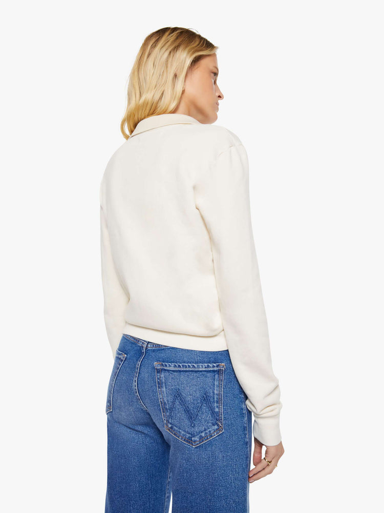 Back view of a woman in a cream  with a collared neck, ribbed hems and a comfortable fit. 