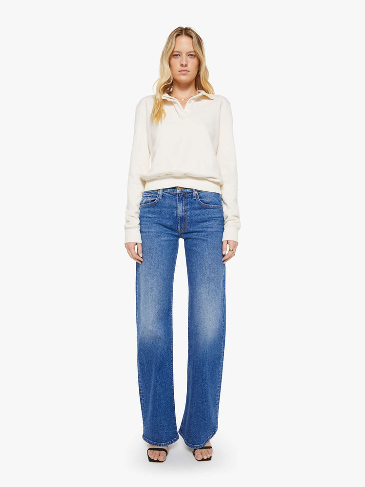Full body view of a woman in a cream  with a collared neck, ribbed hems and a comfortable fit. 