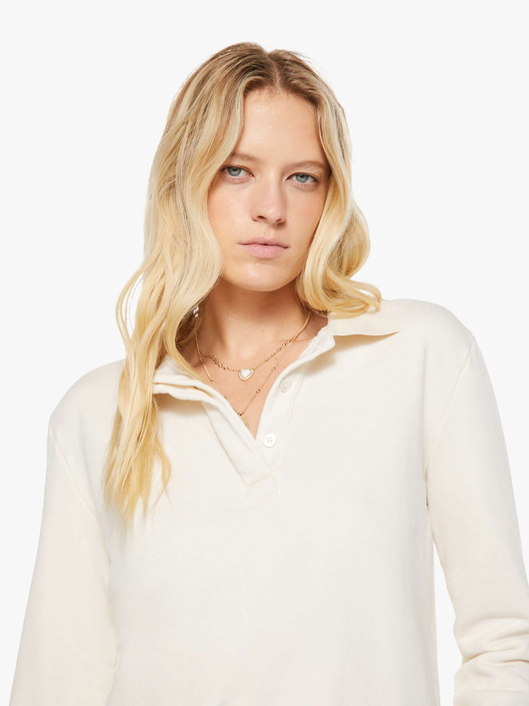 Close up view of a woman in a cream  with a collared neck, ribbed hems and a comfortable fit. 