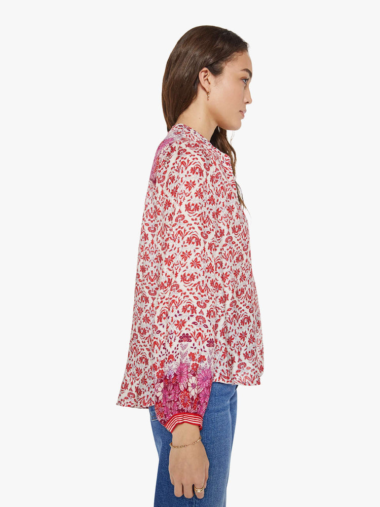 Side view of a woman in cream and pink graphic print buttoned V-neck blouse  and a loose fit.