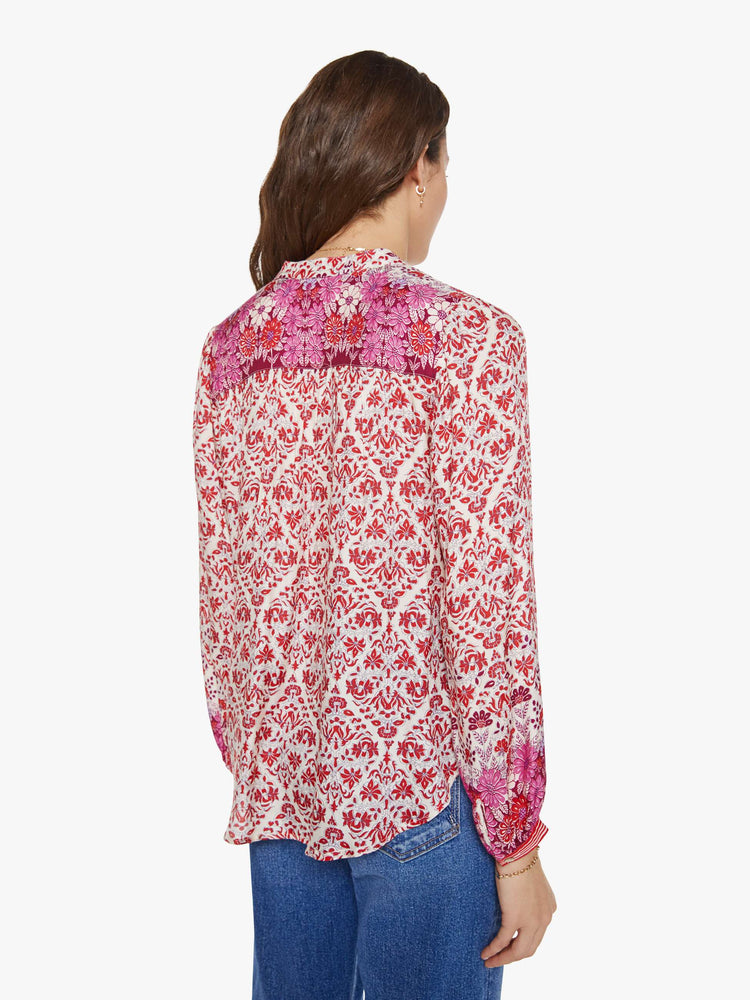 Back view of a woman in cream and pink graphic print buttoned V-neck blouse  and a loose fit.