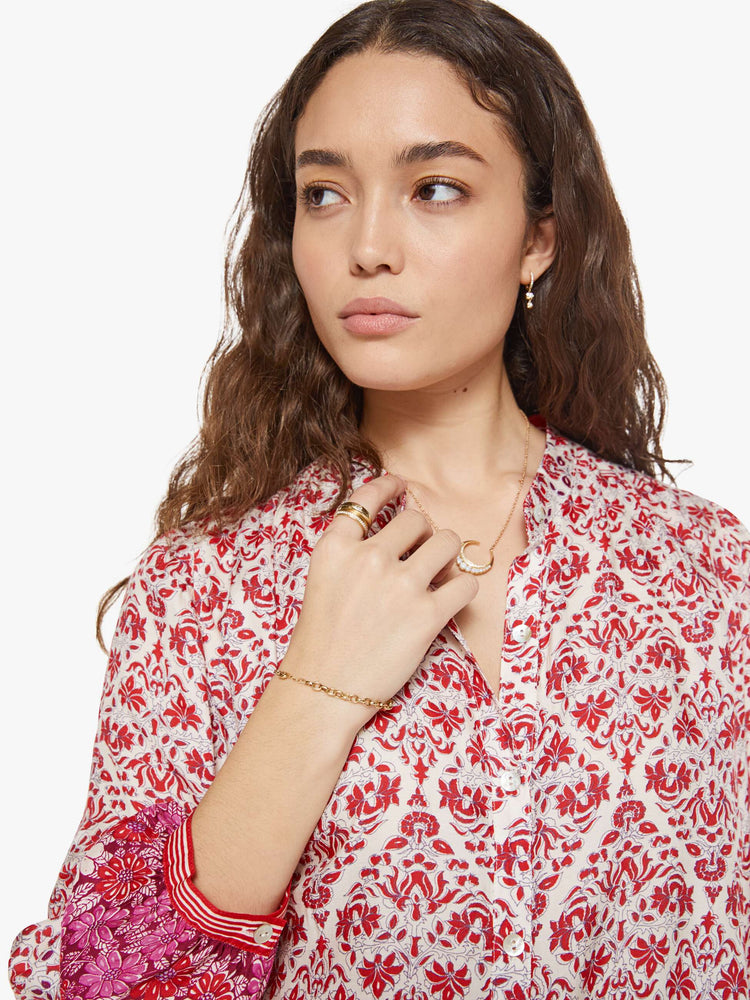 Close up view of a woman in cream and pink graphic print buttoned V-neck blouse  and a loose fit.