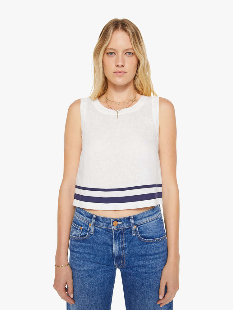 Front view of a woman in a white blouse with navy stripes at the hem.