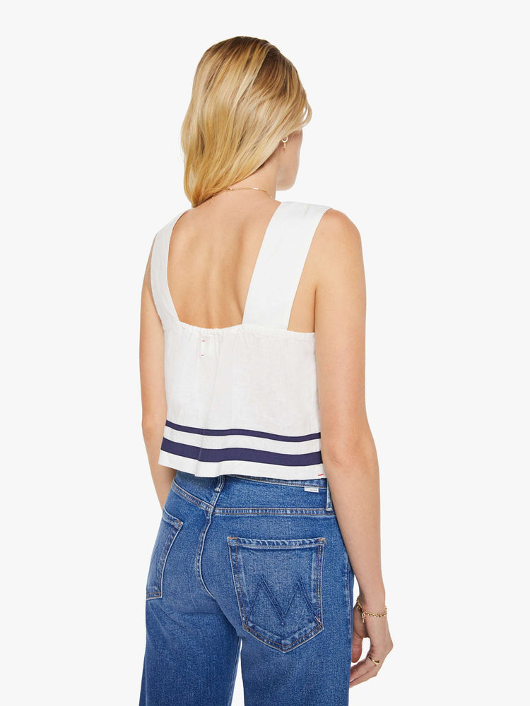 Back view of a woman in a white blouse with navy stripes at the hem.