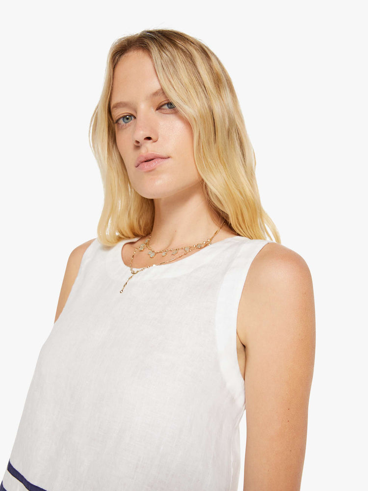 Close up view of a woman in a white blouse with navy stripes at the hem.