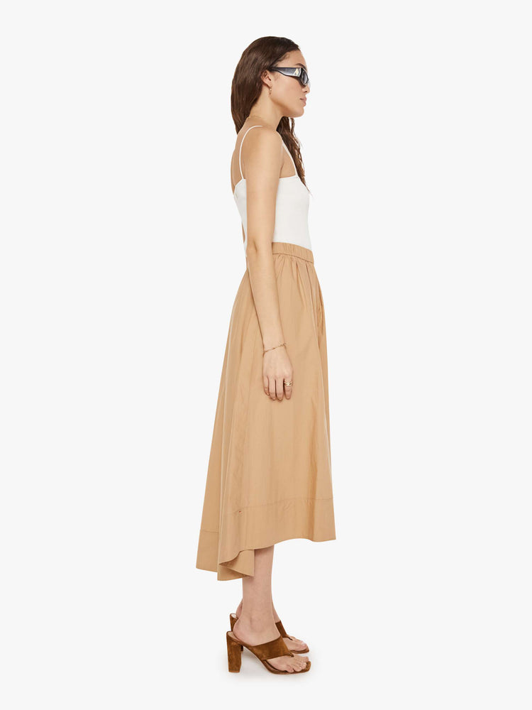 Side view of a woman in a khaki skirt with an elastic waistband, a loose, flowy fit and a curved hem that's slightly longer in the back.