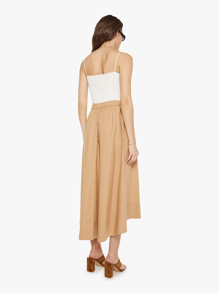 Back view of a woman in a khaki skirt with an elastic waistband, a loose, flowy fit and a curved hem that's slightly longer in the back.