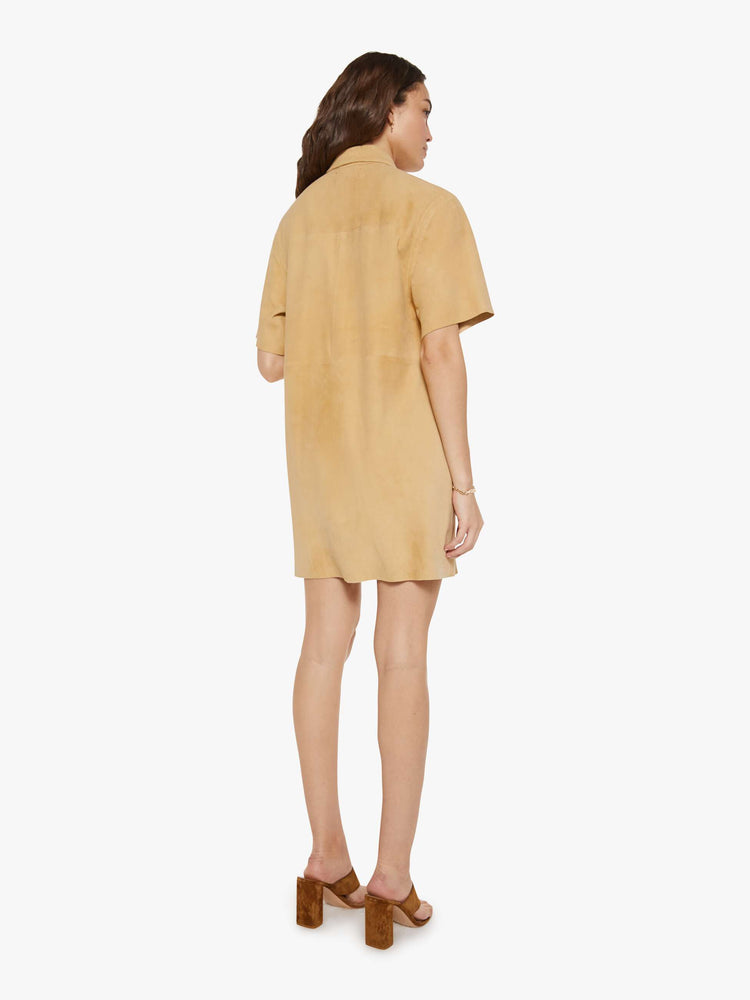 Backview of a woman in a light khaki button up dress with a collared neck, short sleeves and a boxy fit.